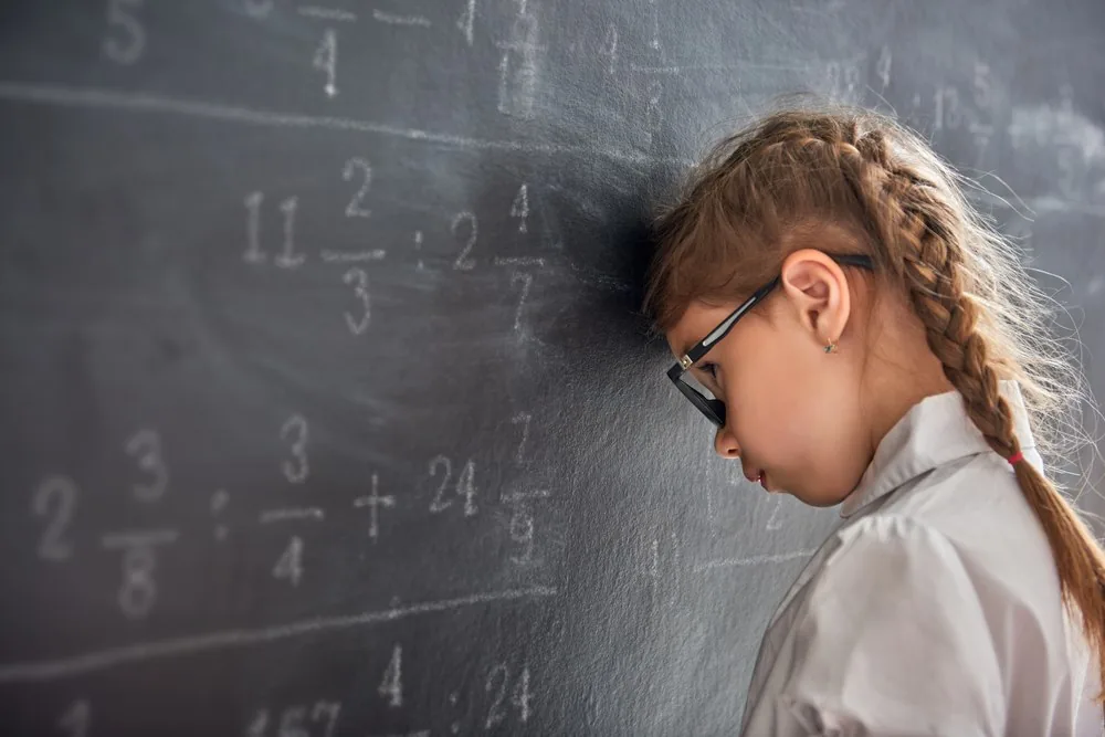 KS2 pupil working through fractions and written maths on a classroom board