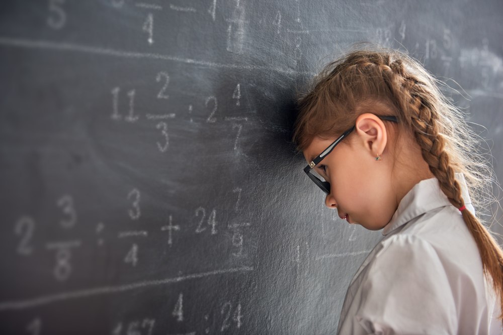 KS2 pupil working through fractions and written maths on a classroom board